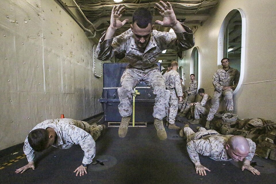 Marines doing burpees, one jumping with arms up while others are in the push-up phase (Wikimedia Commons photo)